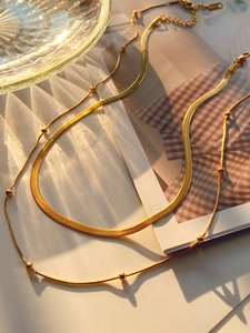 Detailed macro view of 14K gold plated layered snake chain and bead necklace design