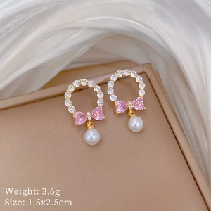 Detailed close-up of pink bow earrings with white pearls on elegant silk background