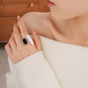 Detail of silver geometric ring with black oval and cream white drip oil enamel inlay