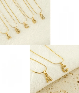 Macro detail of gold-plated stainless steel letter pendants with sparkling zircon stones