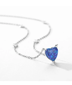 Macro shot of silver heart-shaped opal pendant with small horns and a delicate chain