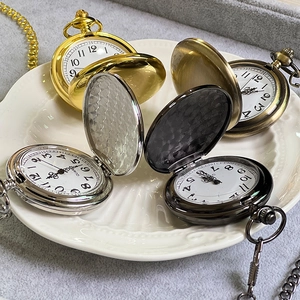Detailed view of metal pocket watches in gold, bronze, silver, and black on a ceramic tray