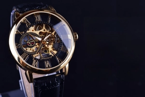 Macro shot of gold stainless steel watch case with skeleton dial and Roman numerals