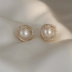 Detailed macro view of an elegant gold pearl stud earring set on premium satin silk fabric