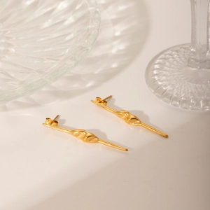 Detailed view of long gold spiral needle earrings with unique twisted metal texture