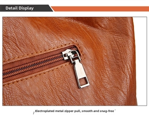 Close-up of silver metal zipper and double stitching on brown lychee texture leather bag