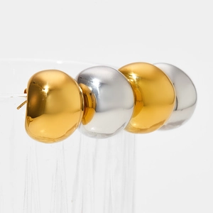 Vue macro détaillée de boucles d'oreilles dôme minimalistes en or et argent sur verre
