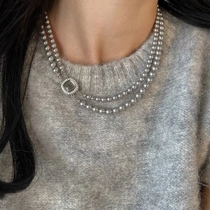 Double-layer grey glass pearl necklace with a square pavé shell pendant on a model