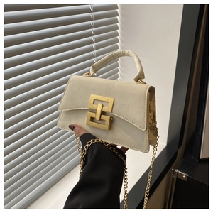 Detail of white PU leather crossbody bag featuring gold interlocking clasp and chain strap