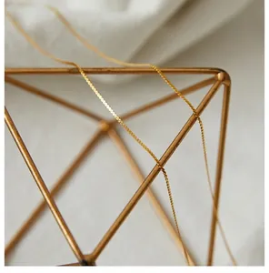 Detail shot of golden wheat chain necklace featuring a polished metallic finish and texture