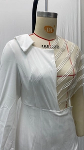 Détail de robe blanche à col en V avec dentelle asymétrique et revers style costume