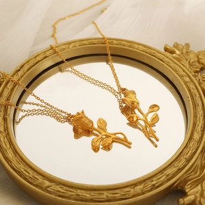 Vintage rose pendant necklace in gold-plated titanium steel on a luxury mirror background