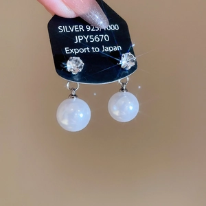 Detail of pearl drop earrings with cubic zirconia and 925 silver studs on black card