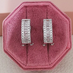 Detailed macro view of U-shaped silver earrings with baguette and round cubic zirconia