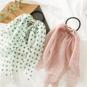 Close-up of chiffon bow scrunchies with green and pink polka dots and gold ring detail