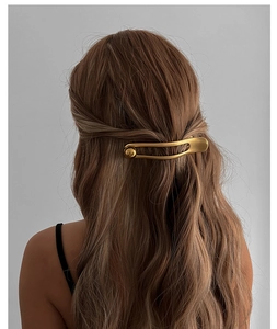 Detail of golden metal hairpin with pearls styled on a model's hair from the back