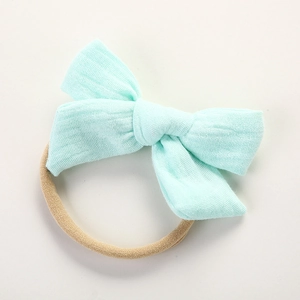 Détail de bandeau bébé avec nœud en mousseline vert pâle sur une bande élastique beige
