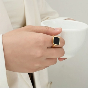 Detail of square black panel ring on hand holding a white cup with minimalist style