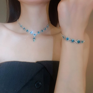 Detail of silver floral jewelry set with blue and clear rhinestones on model's neck