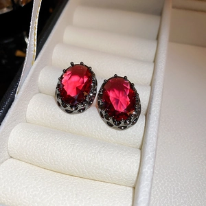 Close-up of vintage oval earrings with red faceted stones and hollow carved metal bases