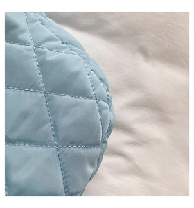 Macro shot of light blue quilted nylon fabric with detailed diamond stitching patterns