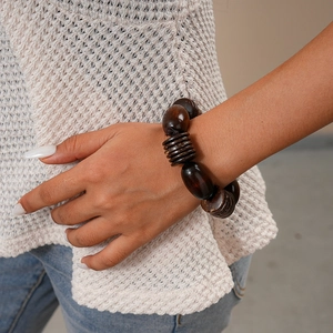 Macro shot of retro dark brown oval wood beads and coconut shell bracelet on wrist
