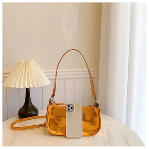 Détail du sac orange métallisé avec poignée à œillets punk et finition miroir