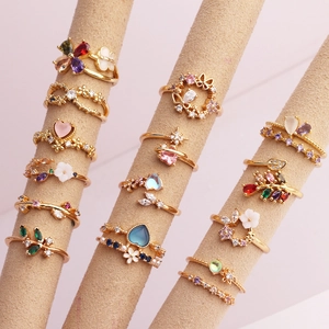 Detailed macro of gold-plated rings with colorful zircon inlays and floral motifs