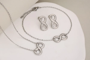 Macro view of polished stainless steel infinity necklace, bracelet and earrings jewelry set