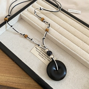 Retro resin wood bead teardrop necklace with black ring pendant on beige jewelry box