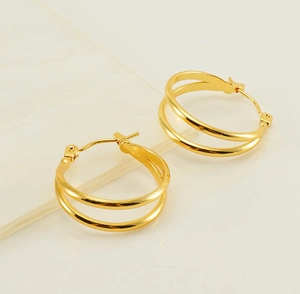 Detail view of double-layered C-shape gold hoop earrings with polished metal finish