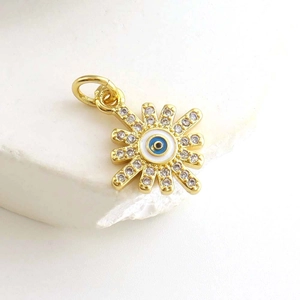 Macro detail of gold plated evil eye sunflower pendant with sparkling zircons