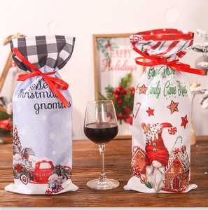 Linen Christmas wine gift bags with festive gnomes and candy patterns on wooden table