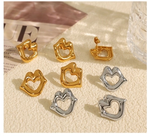 Detailed view of cutout lip and heart-shaped stud earrings in gold and silver finish