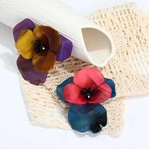Detailed macro view of handmade acrylic floral brooches on a decorative lace background