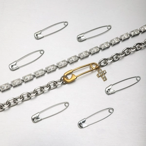 Détail d'un bracelet bicolore avec maillons trombone, pierres zircon et pendentif croix