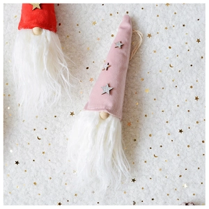 Detail of red and pink plush Christmas gnome ornaments with stars on soft white fur