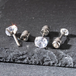 Macro shot of silver stainless steel stud earring with zircon on black stone