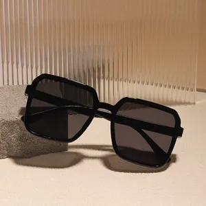 Retro-Sonnenbrille mit schwarzem quadratischem Rahmen und grauen Gläsern auf Stein-Hintergrund