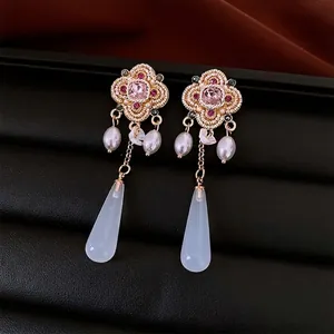 Vintage gold earrings with pink floral gems and light blue resin pendants on black leather