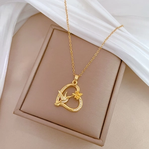 Elegant gold swallow and flower heart pendant necklace with rhinestones on a jewelry box