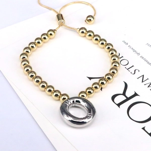 Detail of adjustable gold beaded bracelet with silver O-ring charm and slider clasp