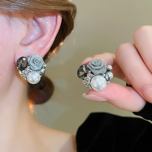 Détail de boucles d'oreilles rose avec perle blanche et cristal gris en argent vieilli