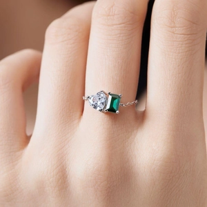 Close-up of S925 sterling silver chain ring with heart and emerald-cut green gems