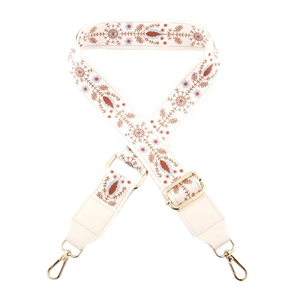 Close-up of beige canvas shoulder strap with ethnic embroidery and gold metal clasps