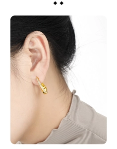 Close-up of minimalist golden C-shaped stud earrings with micro-inlaid zircon stones on ear