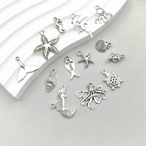 Assorted silver ocean charms including starfish and seahorse on a white decorative stone