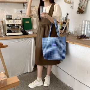 Detail view of a blue and white checkered tote bag featuring a purple brand label