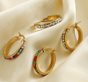 Detail of 18K gold-plated hoop earrings with clear and multicolor crystals on satin