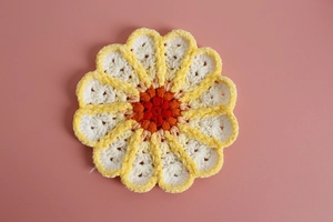 Macro shot of hand-crocheted floral coaster with layered gradient yarn textures